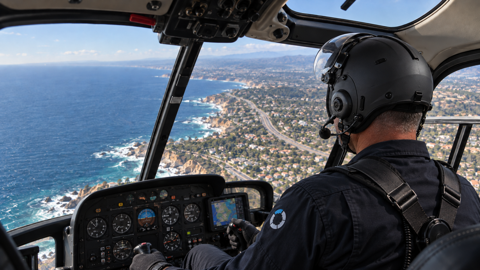 Dr. Ian Purcell in full pilot gear at the controls of a helicopter above the coast